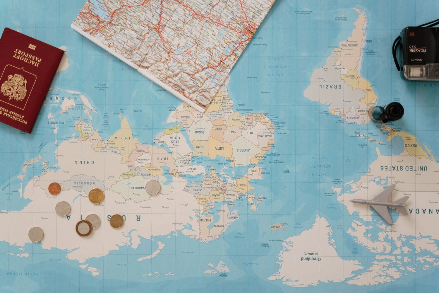 Mapa mundial con un globo terráqueo, un pasaporte, una cámara y un mapa, simbolizando la planificación de un viaje a China.